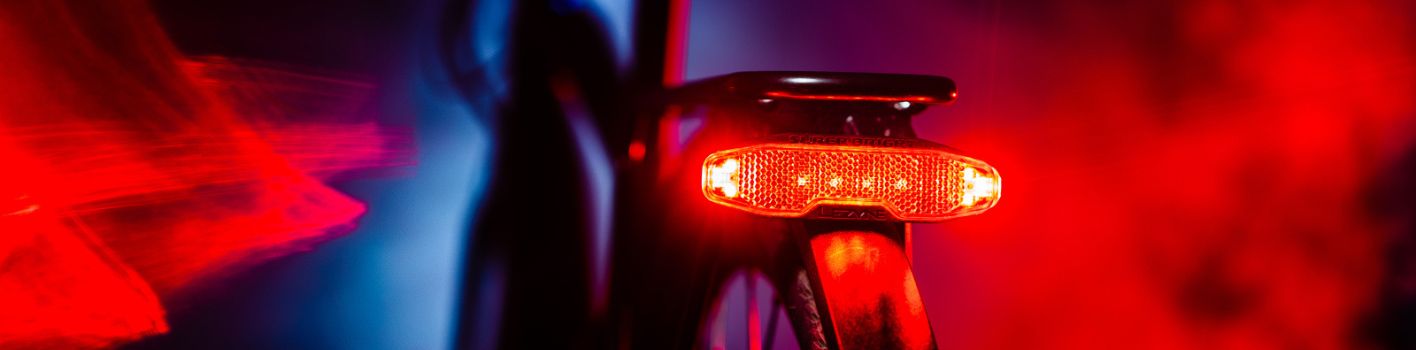 Leuchtendes rotes Fahrradrücklicht im Dunkeln mit einem verschwommenen roten und blauen Hintergrund